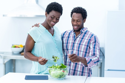 Mulher grávida e marido a preparar uma refeição saudável na cozinha Mulher grávida e marido a preparar uma refeição saudável na cozinha
