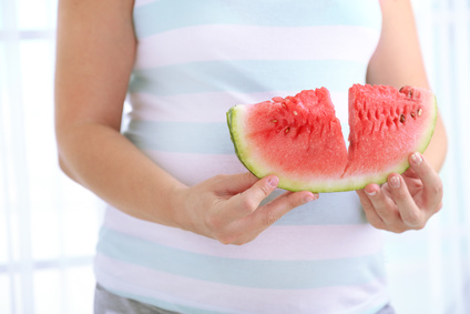Mulher grávida com uma fatia de melancia na mão
