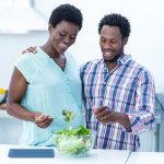Mulher grávida e marido a preparar uma refeição na cozinha
