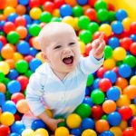 Criança a brincar no meio de bolas coloridas, desenvolvimento cognitivo